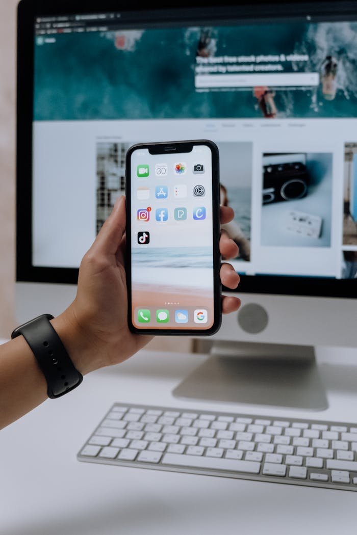 holding a smartphone in front of an imac 5082581